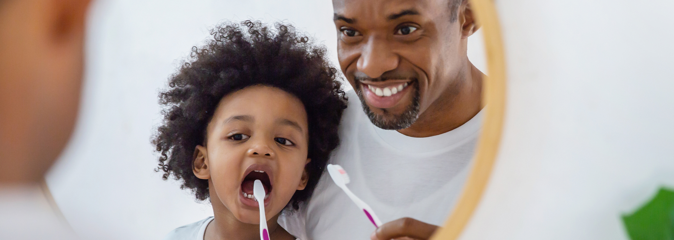 Father helping his child brush their teeth, representing the importance of dental care and the support Dentistry.One provides in care coordination.