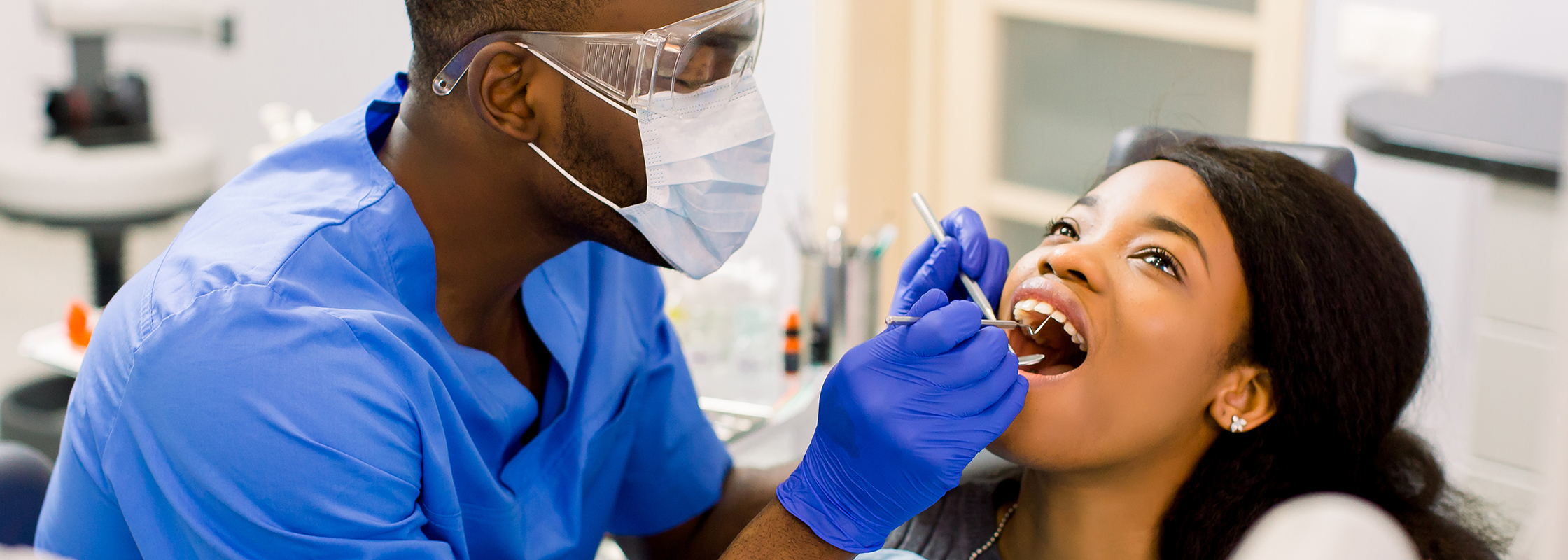 Dentist performing a dental check-up on a younger woman in a clean exam room, representing Dentistry.One’s support for Dental Service Organizations (DSOs).