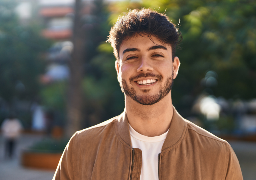 Man standing outside smiling after getting tooth replacement