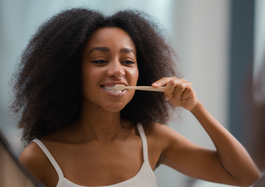 woman looking in mirror showing how to brush teeth properly