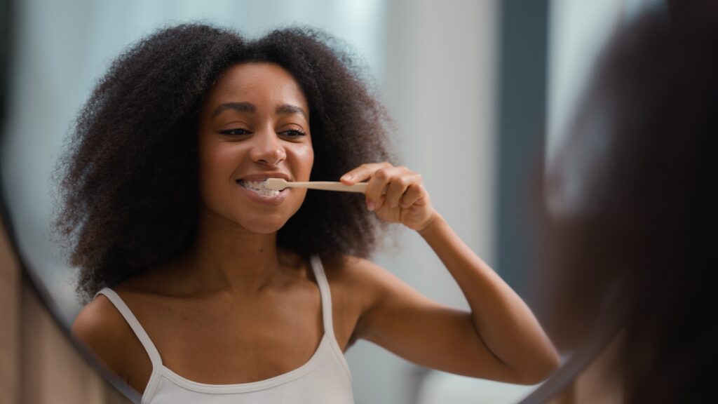 Woman brushing her teeth in the mirror