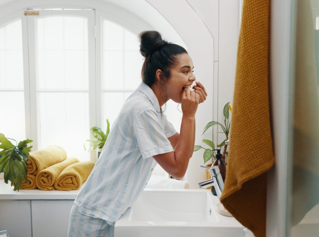 Woman flossing to prevent gum recession
