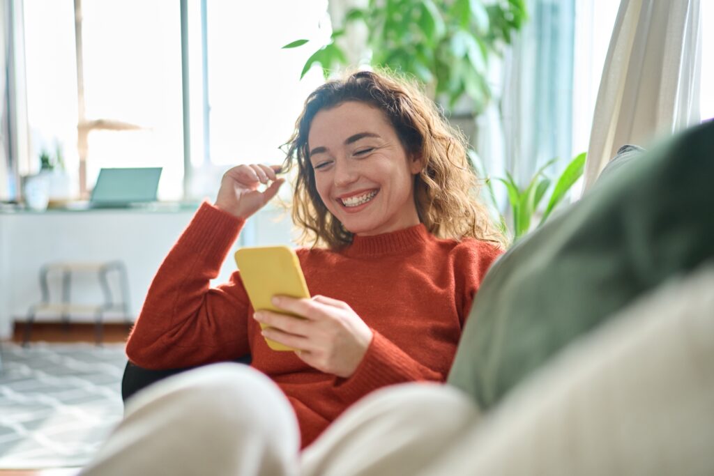 Woman on phone sitting on a couch talking to dentist about teeth grinding